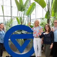 Group of five standing by circle G and giving the Anchors Up symbol to camera